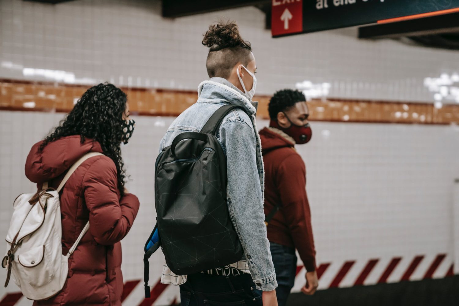 faceless multiethnic students in masks walking in metro